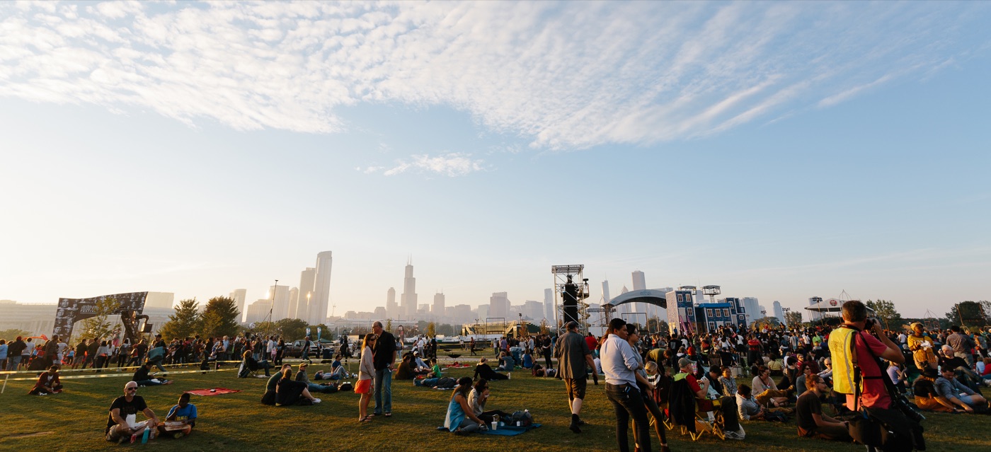 A crowd on the grass at a Chicago summer festival with the skyline behind